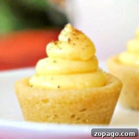 A delightful egg nog cookie cup is filled with creamy yellow eggnog pudding and dusted with nutmeg, elegantly presented on a white plate.