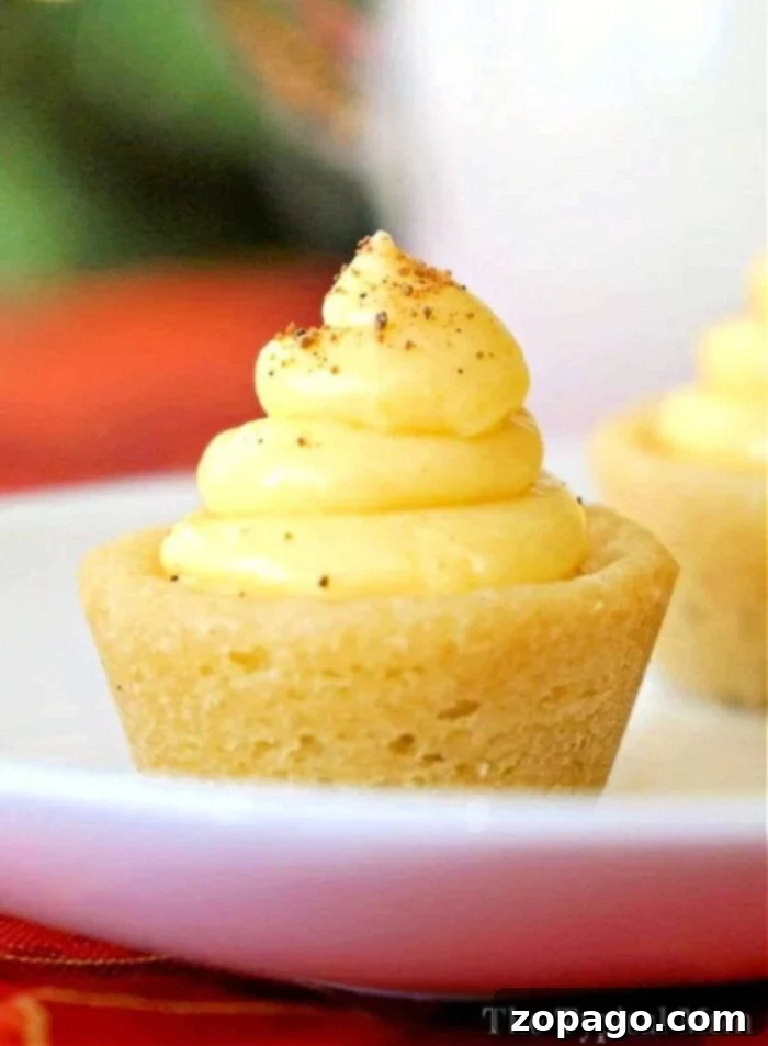 Festive Eggnog Cookie Cups 5 Assortment of mini egg-nog-cookie-cups with various toppings on a white wooden table