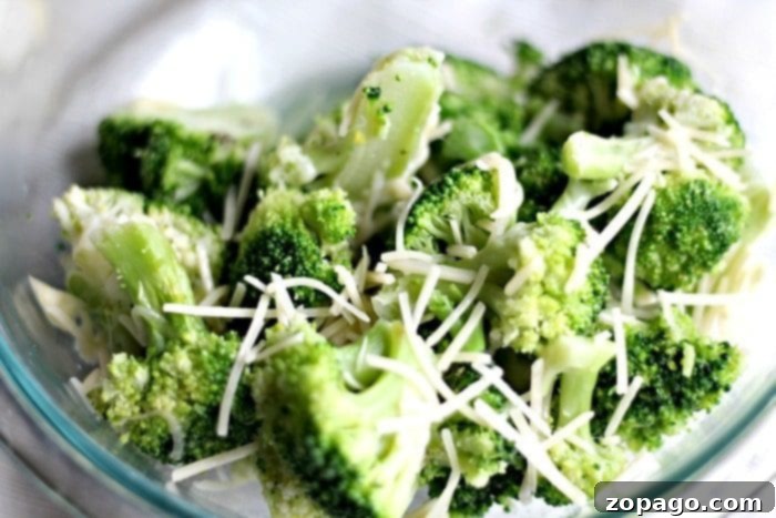 Crisp-Tender Oven Broccoli 4 A vibrant close-up of perfectly prepared broccoli florets in a glass bowl, glistening with olive oil and spices, ready for oven steaming.