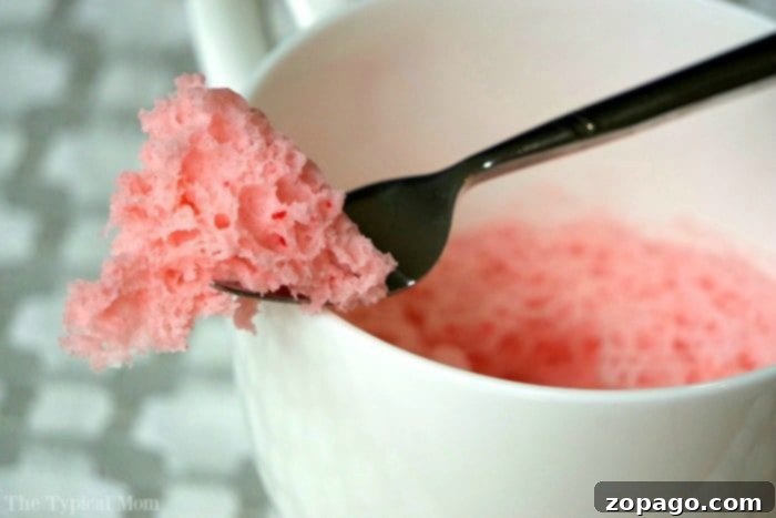 Strawberry cake in a mug recipe that uses just 3 ingredients and takes just 1 minute in the microwave! So moist, it's the perfect dessert for one! #mugcake #cake #microwave #dessert #strawberry #angelfoodcake Strawberry cake in a mug, garnished and ready to be enjoyed.