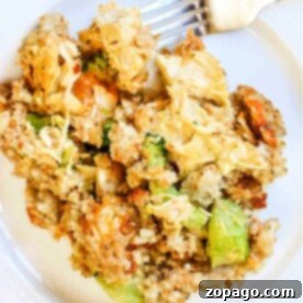 Cheesy Chicken Stuffing Bake 7 A plate of vegetable stuffing with broccoli, carrots, and bread crumbs sits next to a fork, offering a delightful taste that echoes the flavors of a cheesy chicken broccoli casserole without the meat.