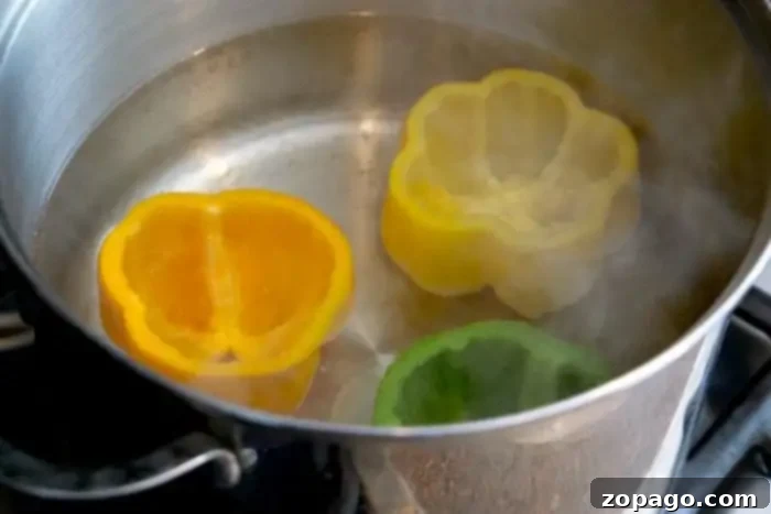 Effortless Bell Pepper Blanching 4 Slices of yellow, orange, and green bell peppers are boiling in a pot of water on the stove, demonstrating how to blanch bell peppers perfectly. Steam rises from the pot.