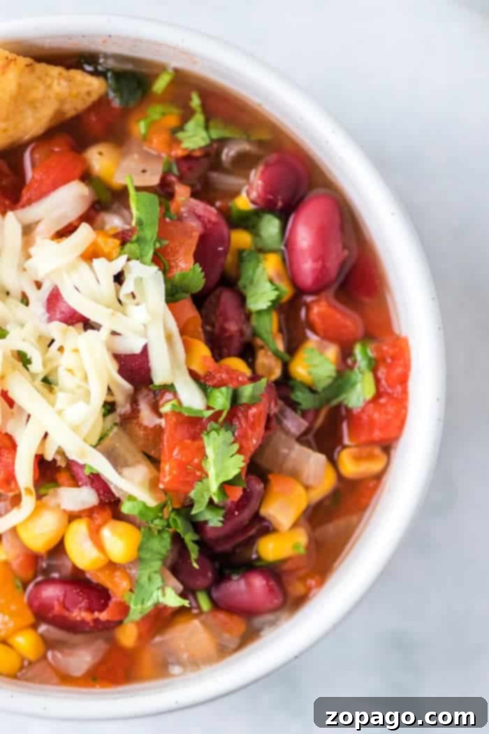 Instant Pot taco soup recipe is perfect year round and packed with flavor. Just 6 minutes in your pressure cooker topped with sour cream and a side of chips or a roll and it's the perfect family meal! Need a warm soup during the Winter or just love anything tacos, give this a whirl. #instantpot #pressurecooker #taco #soup #thetypicalmom #instantpotrecipes A bowl of taco soup with kidney beans, corn, tomatoes, and cilantro topped with shredded cheese captures the essence of an easy instant pot taco soup recipe.