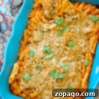 Effortless Chicken Parmesan Bake 2 Baked penne pasta in a blue dish topped with breadcrumbs and garnish, with a colorful cloth beside it, becomes an effortless delight in this no-boil chicken parmesan casserole.