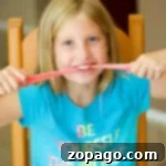 Sweet and Stretchy Gummy Bear Slime 2 Girl in a blue shirt playing with pink, edible slime at a table, smiling broadly.