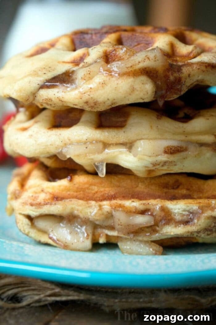 Golden Cinnamon Roll Waffles: A Sweet and Easy Treat Close-up of a delectable stack of cinnamon roll waffles, with rich syrup cascading down onto a blue plate. This image beautifully captures the indulgent essence of cinnamon roll-inspired flavors, highlighting the golden-brown texture.