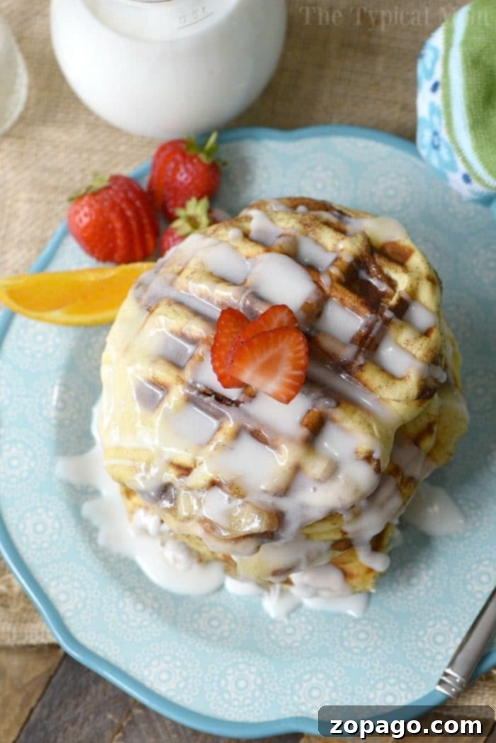 Gourmet Apple Pie Stuffed Cinnamon Roll Waffles Close-up of three beautifully glazed, apple pie stuffed cinnamon roll waffles stacked on a blue plate. The golden-brown texture and dripping glaze are prominent, with a hint of a kitchen background. The image evokes a sense of homemade comfort and indulgence.