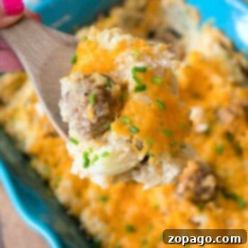 Hearty Hamburger Hash Bake 5 A wooden spoon holds a cheesy ground beef and hashbrown blend over a blue baking dish, reminiscent of a comforting hamburger hashbrown casserole with sour cream.