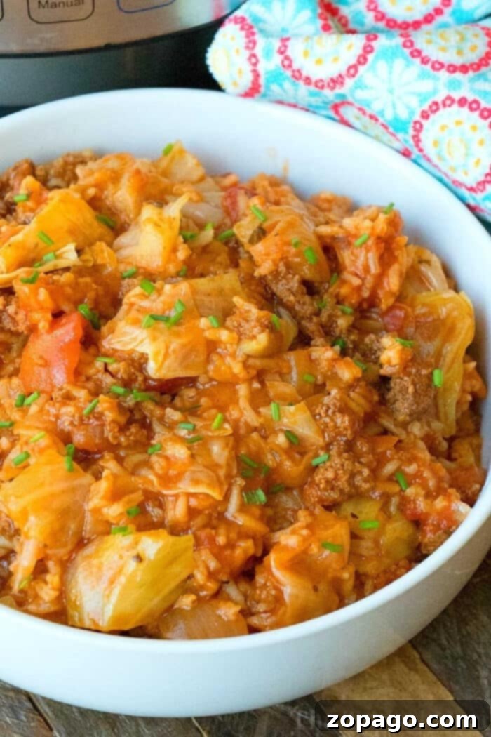 Instant Pot Deconstructed Cabbage Rolls 5 A vibrant Instant Pot unstuffed cabbage casserole, featuring perfectly cooked ground beef, rice, and tender cabbage immersed in a rich, savory tomato sauce, served in a pristine white bowl.