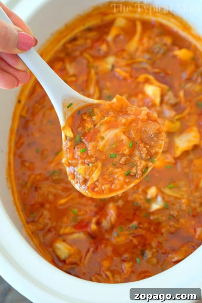 Best Unstuffed Slow Cooker Cabbage Soup Recipe Close-up of a steaming bowl of homemade slow cooker stuffed cabbage soup, garnished with fresh parsley, highlighting the tender cabbage, ground sausage, and rich tomato-based broth.