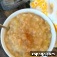 Homemade Ninja Foodi Applesauce 4 A bowl of apple cinnamon applesauce sits invitingly beside a pressure cooker, with a floral cloth adding a touch of charm, ready to be enjoyed.