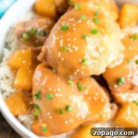 Enjoy this easy pineapple chicken: glazed chicken and pineapple chunks over rice, garnished with sesame seeds and chopped green onions.