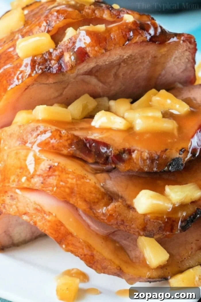 BEST Instant Pot ham done in just 20 minutes! If you want an easy honey ham recipe you've gotta' try it in your pressure cooker. #instantpot #ham #honey #pressurecooker #instantpotrecipes #thetypicalmom #ninjafoodi #glaze Sliced glazed ham, tender from the instant pot, topped with chunks of pineapple on a white plate.