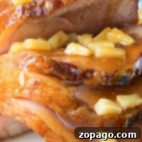 Effortless Instant Pot Ham 3 A close-up of glazed ham slices, cooked to perfection in an Instant Pot, topped with succulent pineapple chunks.