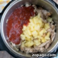 Instant Pot Hawaiian pulled pork with tender shredded pork, juicy pineapple chunks, and a rich red sauce on top.
