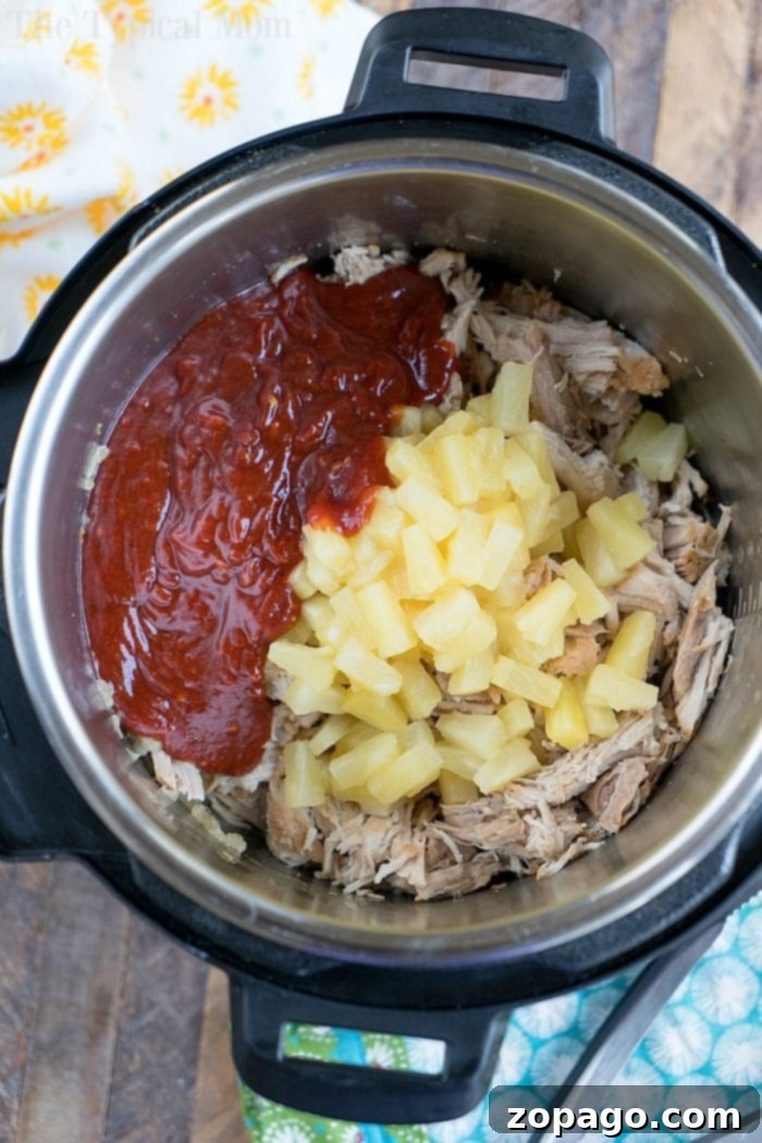 Easy Instant Pot Hawaiian Pulled Pork 4 Instant Pot Hawaiian pulled pork with tender shredded pork, juicy pineapple chunks, and a rich red sauce on top.