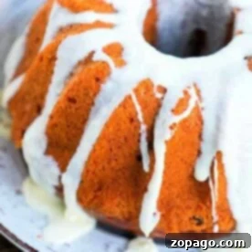 Bundt cake with white icing drizzled on top, crafted to perfection in a Ninja Foodi, served elegantly on a white plate.