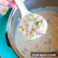 Corned Beef Revival Soup 4 A spoonful of creamy corned beef soup with ham and green onions hovers above the pot, promising a savory delight.