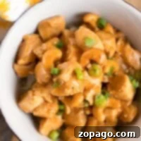 Easy Instant Pot Cashew Chicken 5 A bowl of pressure cooker cashew chicken, garnished with green onions, rests enticingly on a wooden table.