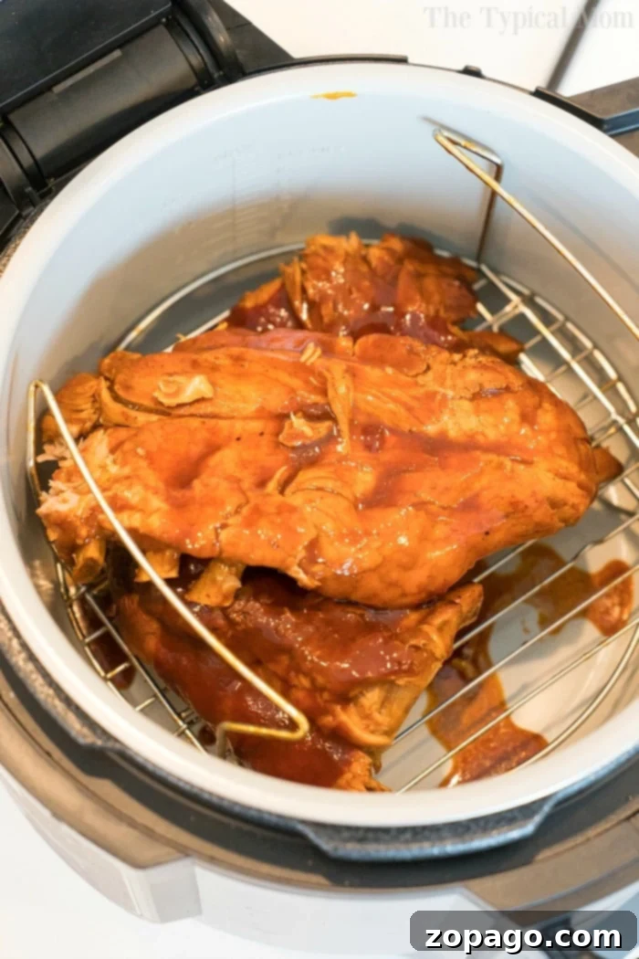 The initial tenderizing stage of Ninja Foodi ribs, showcasing succulent pressure-cooked ribs before air crisping. Succulent pressure cooker ribs, perfectly tender and ready for the finishing air crisp.
