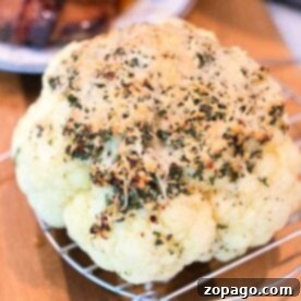 Perfect Whole Pressure Cooker Cauliflower 5 Whole pressure cooker cauliflower topped with herbs and cheese sits on a rack, with grilled meat in the background.