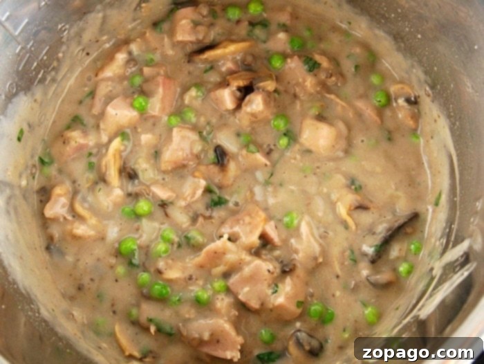 Velvety Homemade Cream of Mushroom Soup 3 A pot of creamy homemade cream of mushroom, brimming with tender pieces of chicken, peas, and mushrooms.