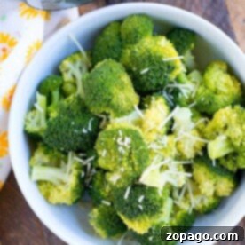 Effortless Instant Pot Side Dishes 11 A bowl filled with freshly cooked broccoli florets, sprinkled with grated cheese, makes a perfect instant pot side dish. Positioned on a wooden surface next to your trusty Instant Pot pressure cooker, it sits elegantly beside a white cloth adorned with yellow flowers.