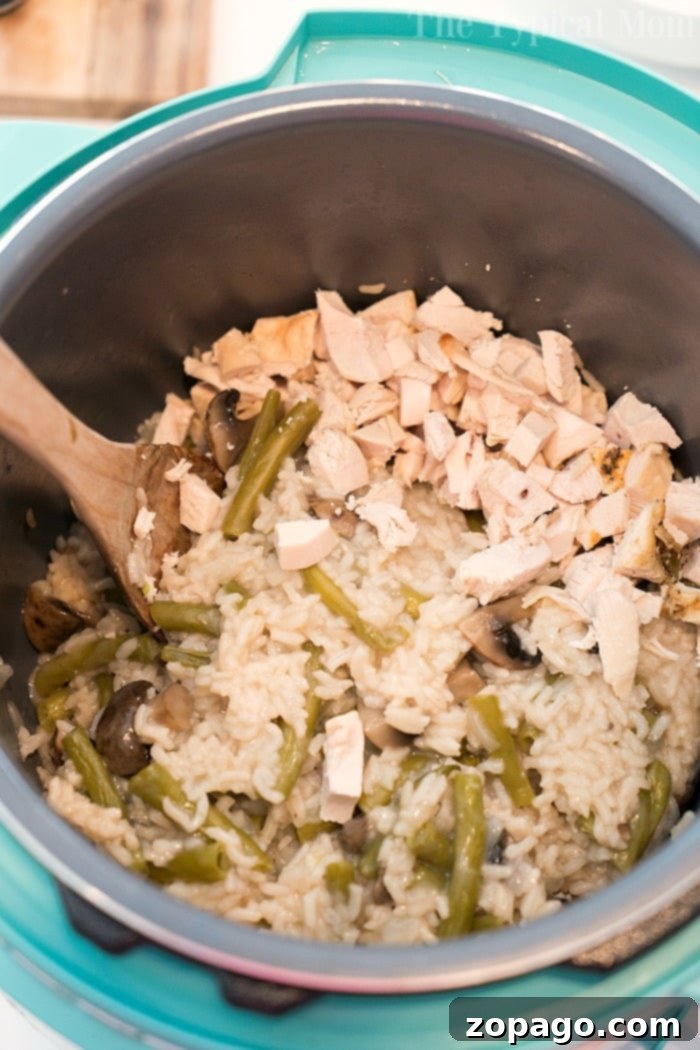 Instant Pot Chicken Mushroom Casserole: A delightful, easy-to-make comfort food packed with tender chicken, rice, mushrooms, and green beans, perfect for the whole family. A pressure cooker filled with a creamy chicken, mushroom, and green bean rice casserole, stirred gently with a wooden spoon, showcasing the perfectly cooked ingredients.