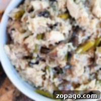 A creamy, rich pressure cooker chicken mushroom casserole with rice, green beans, and melted cheese, served in a bowl on a rustic wooden table.