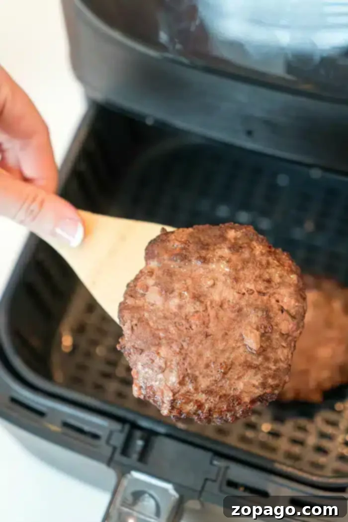 How long to cook frozen hamburger in an air fryer so it's juicy! If you forgot to defrost ground beef for dinner, don't fret we've got you covered here. #airfryerrecipes #airfryerhamburgers #frozenhamburgers #airfryer #thetypicalmom Air fryer frozen burgers cooking