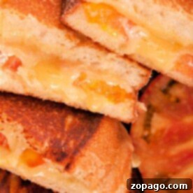 Close-up of grilled cheese sandwiches with melted cheese and tomato slices inside, stacked together—perfectly crisp like a grilled cheese in air fryer.