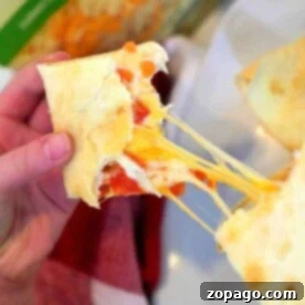 Close-up of a hand pulling apart an air fryer quesadilla with salsa, revealing the delightful strands of melted cheese.