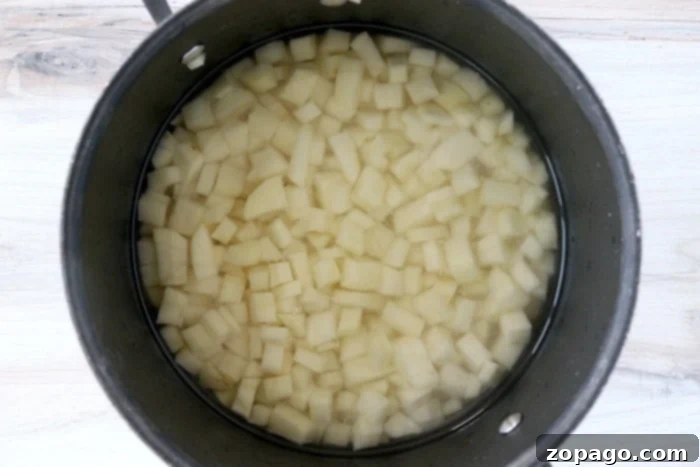 Creamy Cheesy Potato Bake 4 Perfectly diced raw potatoes, uniform in size and ready for boiling, laid out on a clean white surface.