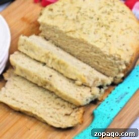 No-Knead Slow Cooker Wonder 3 A loaf of slow cooker bread, partially sliced, rests on a wooden cutting board beside a blue-handled knife.