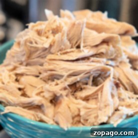 Tender shredded cooked chicken piled high in a blue bowl—see How to Make Shredded Chicken on the Stove for this easy and delicious result.