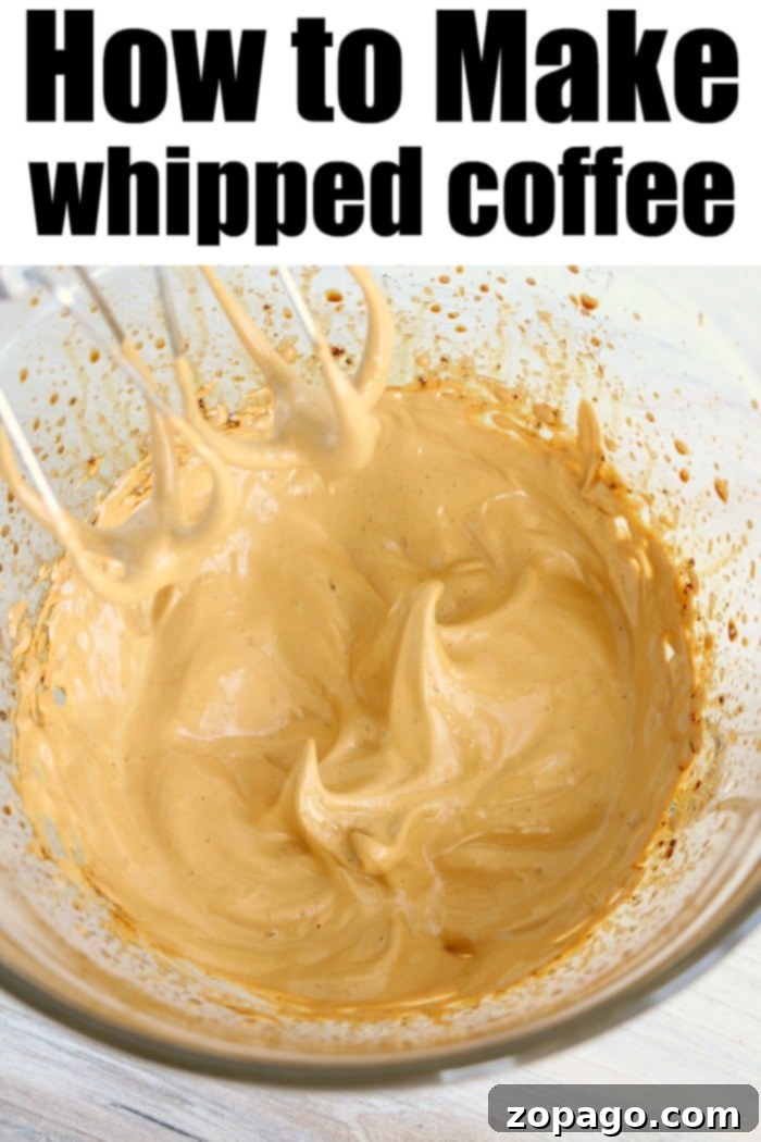 Dalgona whipped coffee recipe! EASY to make this popular TikTok drink everyone is going crazy over. I bet you'll love it too. Close-up of fluffy, golden-brown Dalgona whipped coffee foam in a glass, ready to be mixed with milk.