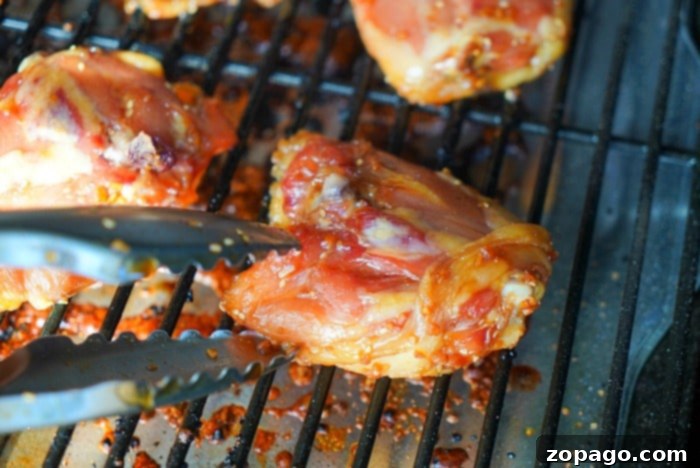 Perfectly Smoked Traeger Chicken Thighs 8 Close-up of barbecued chicken thighs, showing crispy skin and juicy meat, garnished with fresh herbs.