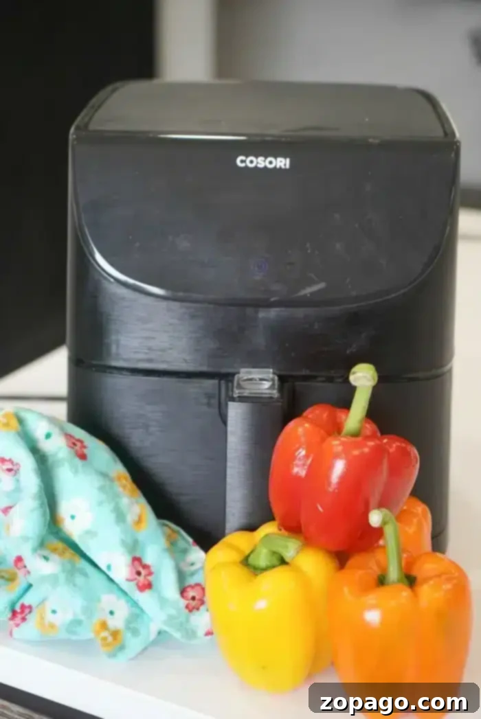 Air-Fried Bell Peppers: Quick, Easy, and Flavorful 4 A sleek black air fryer sits proudly on the countertop, flanked by vibrant red, yellow, and orange bell peppers, ready for cooking.