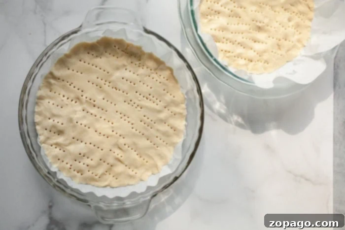 No-Bake Christmas Tree Cookies 4 Two pie dishes on a marble surface, with fork marks on the cookie dough, evoke the charm of baking Christmas tree sugar cookies during the festive season.
