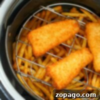Golden fish fillets and crispy fries sizzling, making a delightful serving of air fryer fish and chips.