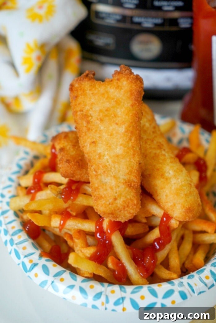 Crispy Air Fryer Fish and Chips 8 Fish and chips cooking in an air fryer, with a trivet separating the two components for optimal crispiness.