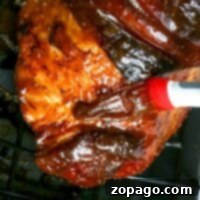 Sweet Bourbon Glazed Ham 6 Close-up of bourbon glazed ham sizzling on a grill rack, being brushed with barbecue sauce.