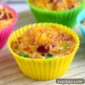 A close-up of colorful cupcake molds filled with air fryer egg bites on a wooden surface showcases the deliciously baked muffins.