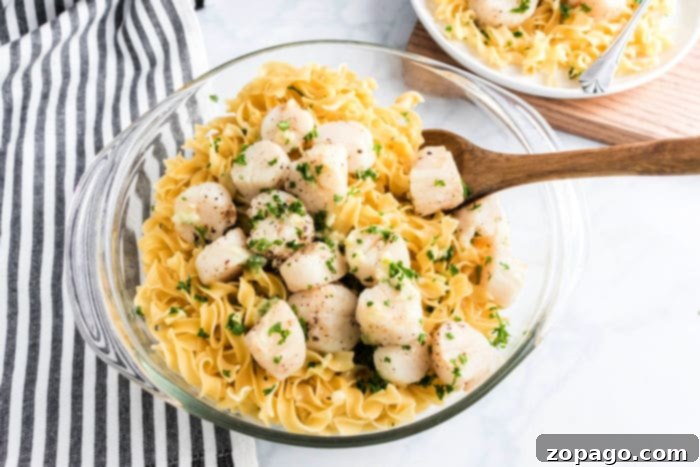 Golden Air Fryer Scallops 8 Bowl of pasta topped with air fryer scallops and chopped herbs, served with a wooden spoon.