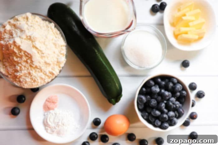 Heavenly Zucchini Blueberry Muffins 4 A vibrant assortment of fresh ingredients laid out on a kitchen counter, including blueberries, shredded zucchini, flour, sugar, butter, and eggs, ready for making zucchini blueberry muffins.