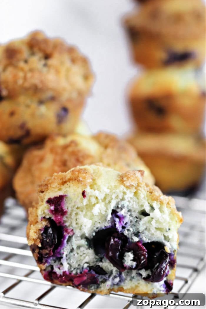 Heavenly Zucchini Blueberry Muffins 10 A stack of golden, freshly baked homemade muffins on a cooling rack, steam gently rising, ready to be enjoyed.