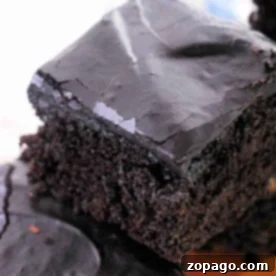 Hidden Veggie Brownies 6 Close-up of a stack of chocolate brownies with a glossy, cracked top layer. Imagining these as part of a zucchini brownie recipe enhances their moist and dense texture, showcasing a rich, dark brown color.
