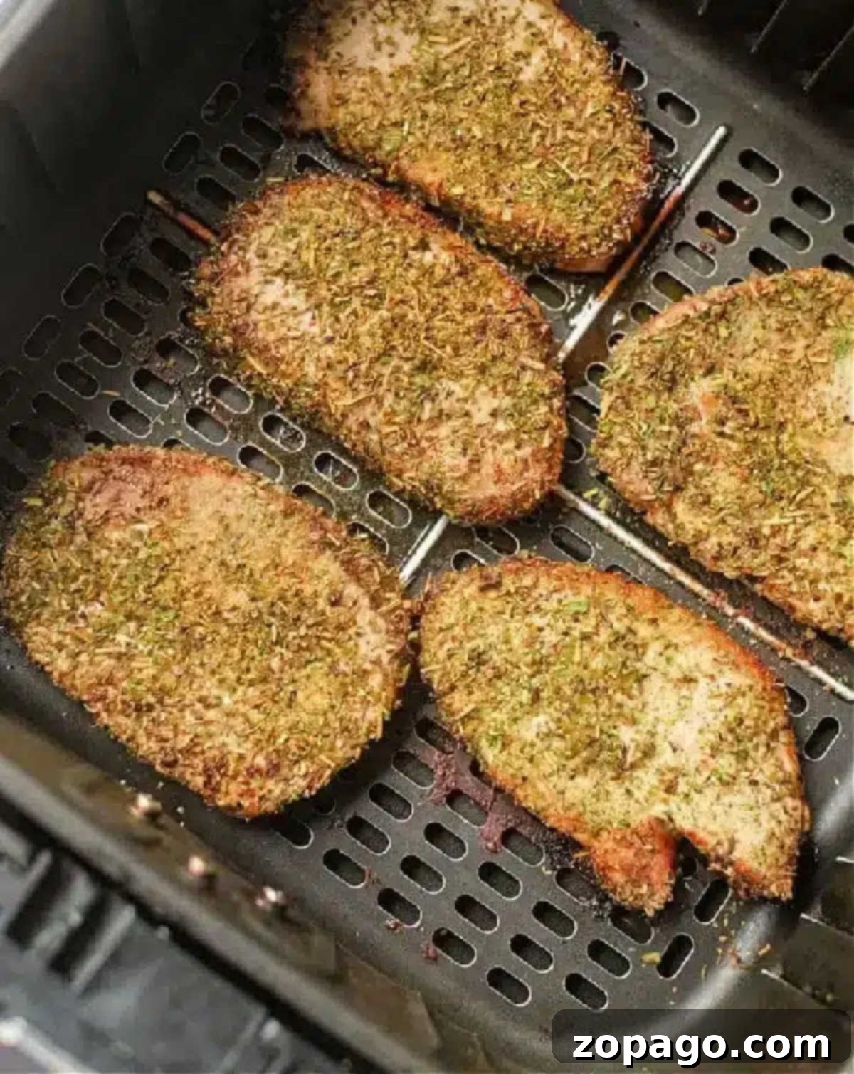 Perfect Air Fryer Pork Steak 7 Seasoned pork chops, or pork steak in air fryer, cook to golden brown perfection, evenly spaced in the basket.
