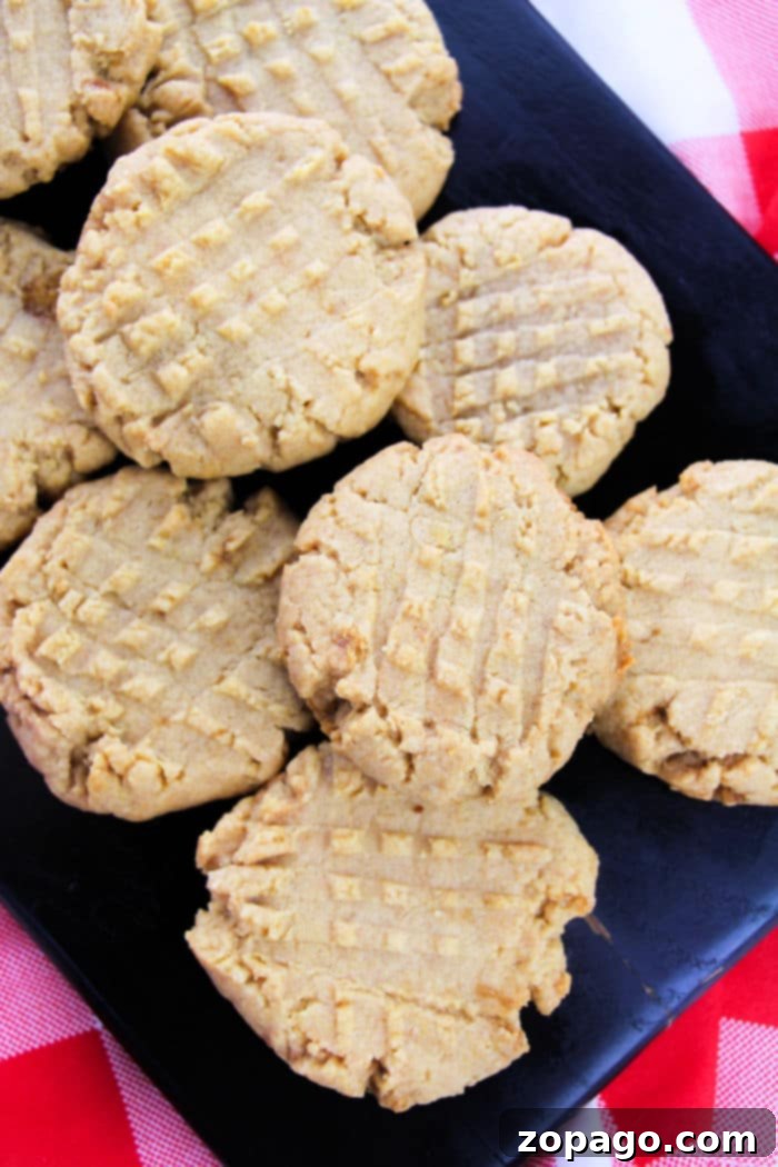Effortless Four Ingredient Peanut Butter Cookies 5 A fresh batch of the best peanut butter cookies, golden-brown with classic fork marks, arranged on a cooling rack.