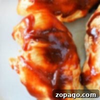 Instant Pot From Frozen Chicken Breast in Sauce 6 Tender chicken breasts cooked to perfection in an instant pot, covered with a rich barbecue sauce, are served on a pristine white plate.